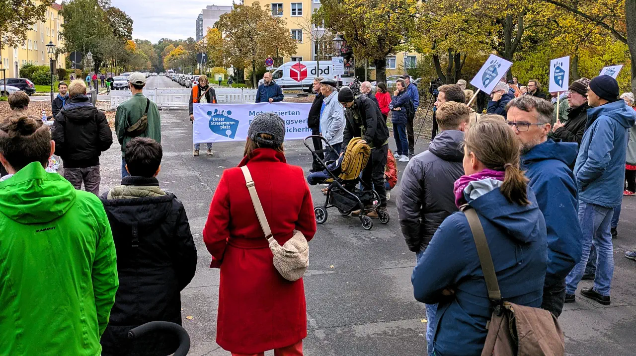 Kundgebung der Bürgerinitiative 'Unser Stresemannplatz' in Dresden. Menschen stehen auf einer gesperrten Straße im Herbst, halten ein Banner und Schilder. Die Demonstration fordert Verkehrswende, mehr Sicherheit und eine lebenswerte Stadtentwicklung am Stresemannplatz.